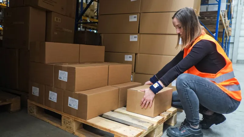 Mitarbeiterin mit Messset in ergonomischer Haltung an einer Palette